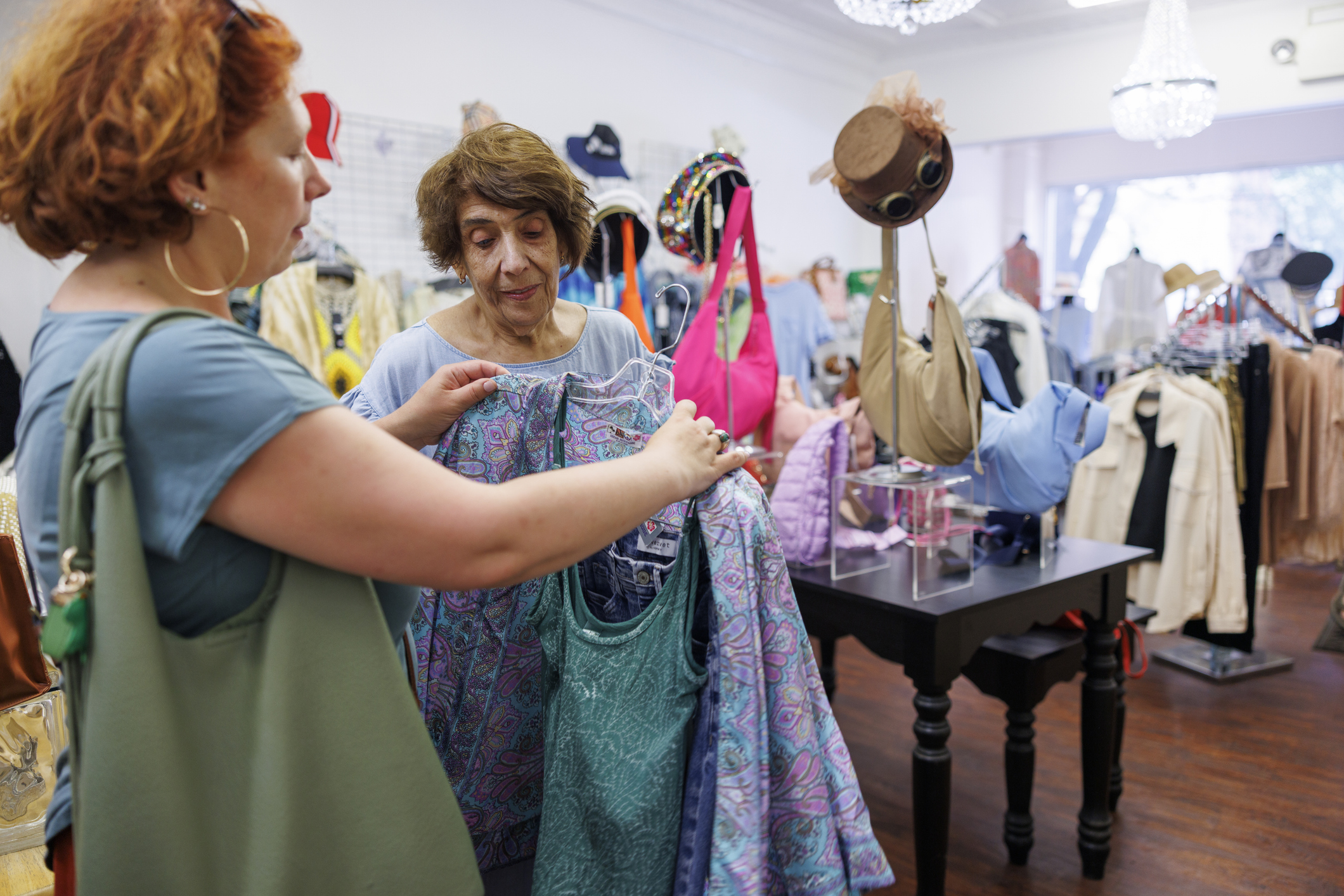 Two women looking at clothing together in a thrift store